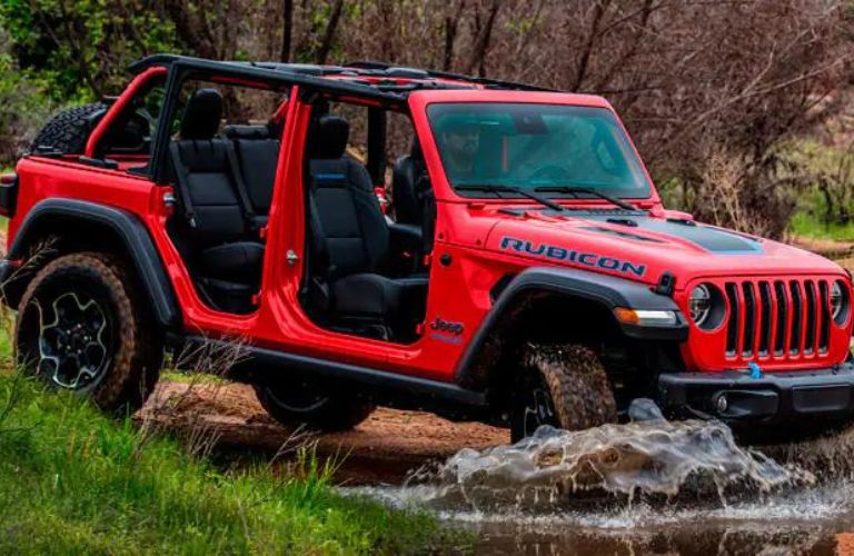 Side view of a red 2022 Jeep Wrangler crossing a rough terrain